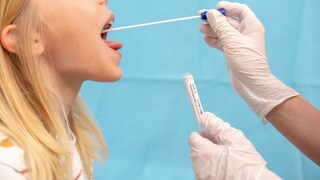 A child is given a throat swab test for COVID-19.