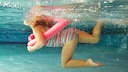 A girl swims with a pool noodle
