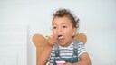 A toddler eats yogurt.