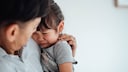 Man Holds a Crying Child in His Arms