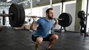 Improved Muscle Growth: Man Performs Squats with Barbell