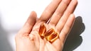 Person Holds Omega-3 Capsules in Hand