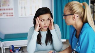 Woman sits annoyed next to a doctor
