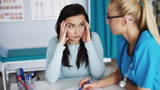 Woman sits annoyed next to a doctor