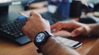 A man with a smartwatch smokes at his desk