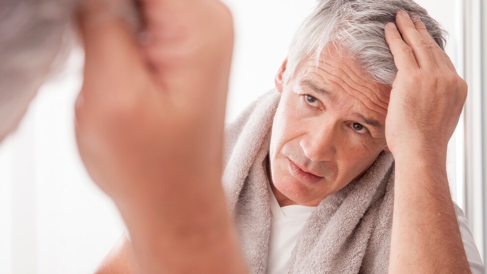 A man runs his fingers through his gray hair