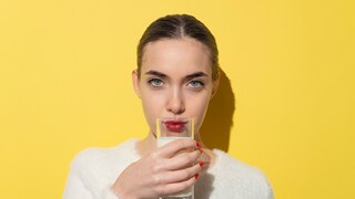 A woman drinks a glass of milk.