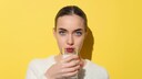 A woman drinks a glass of milk.