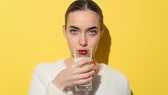 A woman drinks a glass of milk.