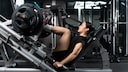 A woman trains with heavy weights on the leg press.