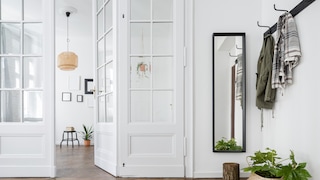 A bright hallway with a coat rack and narrow mirror