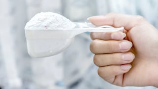 A hand holds washing powder in a ladle