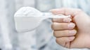 A hand holds washing powder in a ladle