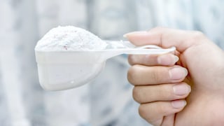 A hand holds washing powder in a ladle