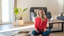 A woman sits on two overlapping rugs: a flat-woven kilim and a sisal rug.