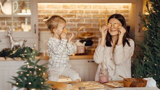 Baking Cookies with Kids: A mom holds cookies in front of her face. Her daughter imitates her.