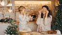 Baking Cookies with Kids: A mom holds cookies in front of her face. Her daughter imitates her.