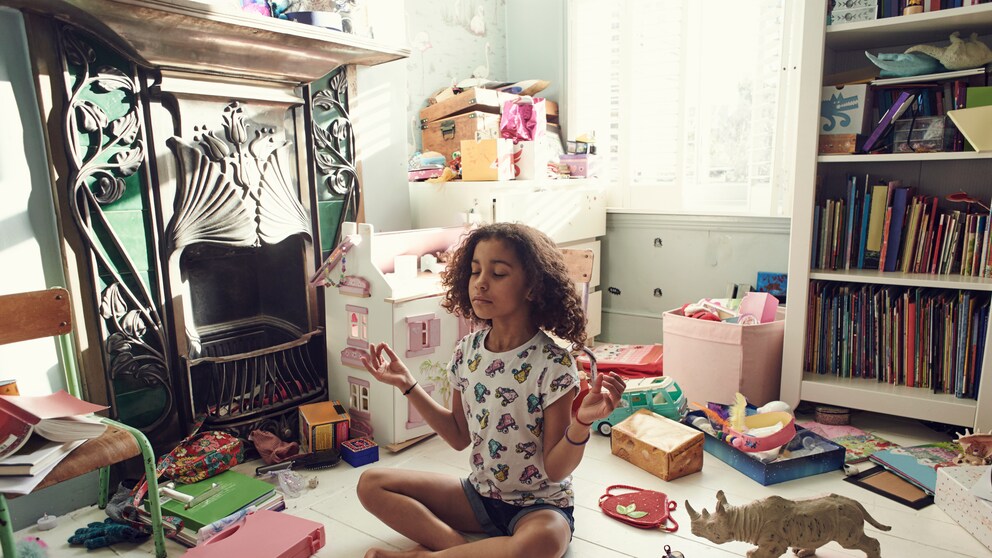 Little girl seemingly meditating amid the chaos of her playroom
