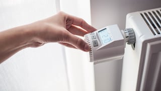 A woman adjusts the temperature on a digital thermostat