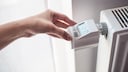 A woman adjusts the temperature on a digital thermostat