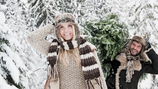 Cutting Your Own Christmas Tree: A Couple Smiles as They Carry a Christmas Tree Through a Winter Snow Landscape