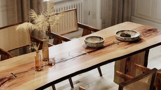 Long wooden table in sunlight with colorful vases and ceramics