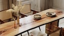 Long wooden table in sunlight with colorful vases and ceramics