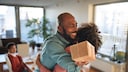 Father hugs child with a gift in hand.