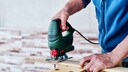 Man Uses Jigsaw to Cut a Piece of Wood
