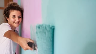 Young Woman Paints Her Wall Colorfully with Emulsion Paint