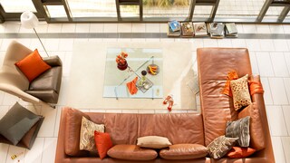 Living room with a brown leather sofa and orange cushions