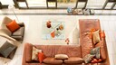 Living room with a brown leather sofa and orange cushions