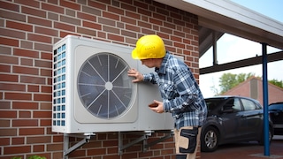 Man with helmet next to a heat pump