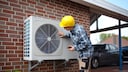 Man with helmet next to a heat pump