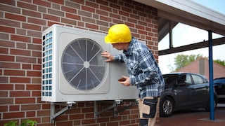 Man with helmet next to a heat pump