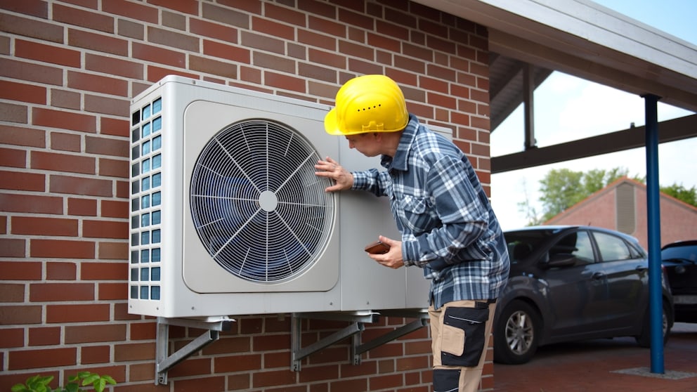 Man with helmet next to a heat pump