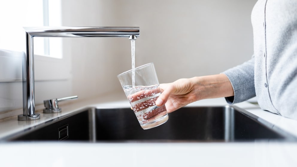 Someone pours tap water into a glass