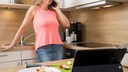 A woman is having a phone conversation in the kitchen.