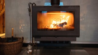 A sooty glass pane on the wood stove limits the view of the roaring fire.