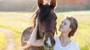 Woman Stands Next to Her Horse on a Country Path