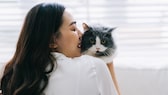 A young woman holds a cat she doesn't like