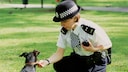 Police officer in London bends over a dog to check its tag