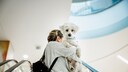 A woman carries her small dog on the escalator