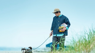 Man with dog holds books in his arms