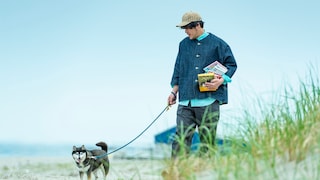 Man with dog holds books in his arms