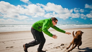 Dog owner chases his dog on the beach