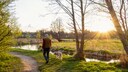 A man and his dog are walking by a river