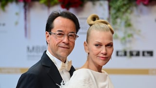 Jan Josef Liefers and his wife, Anna Loos, pose on a red carpet.