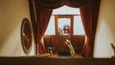 An excited dog jumps up at the front door to greet a woman and child peering through the window—a familiar scene for pet owners.