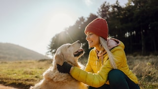 Young woman holds the head of a golden retriever in her hands